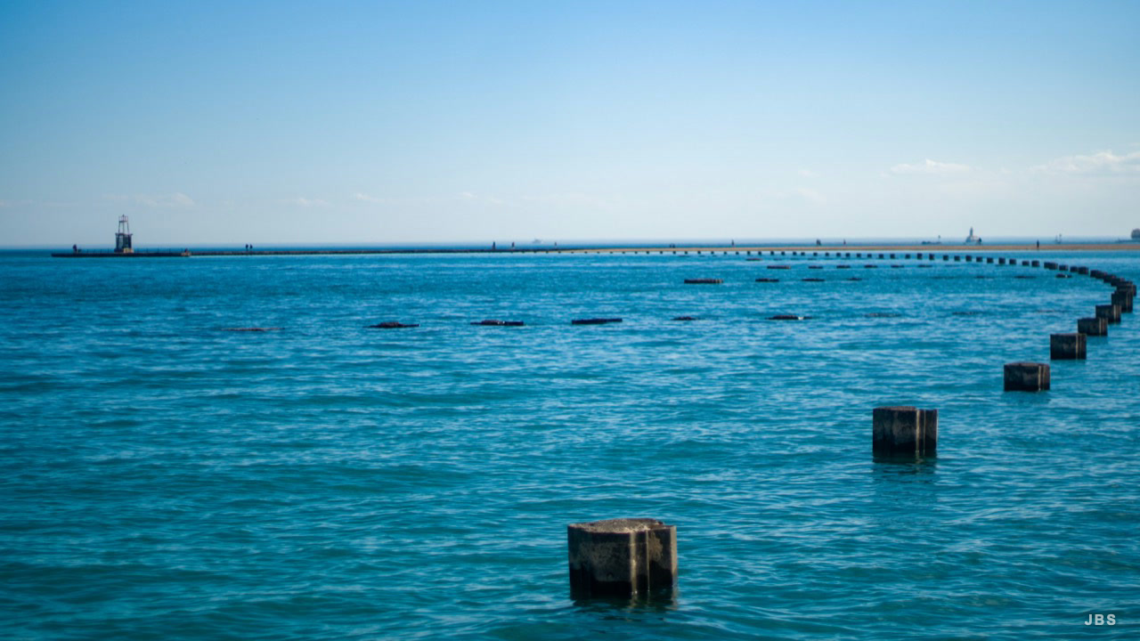Rows of weathered pilings receding across bright blue water