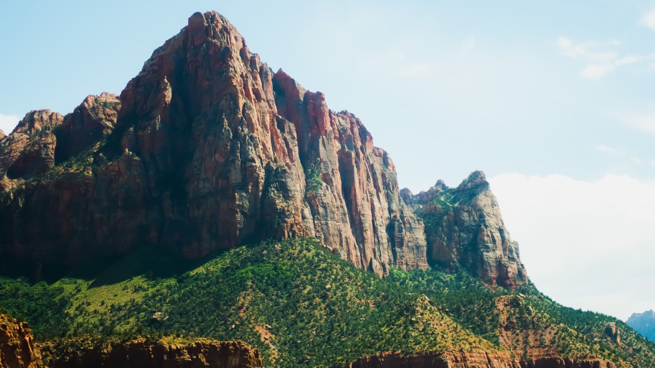 Red sandstone cliffs rising above green foothills