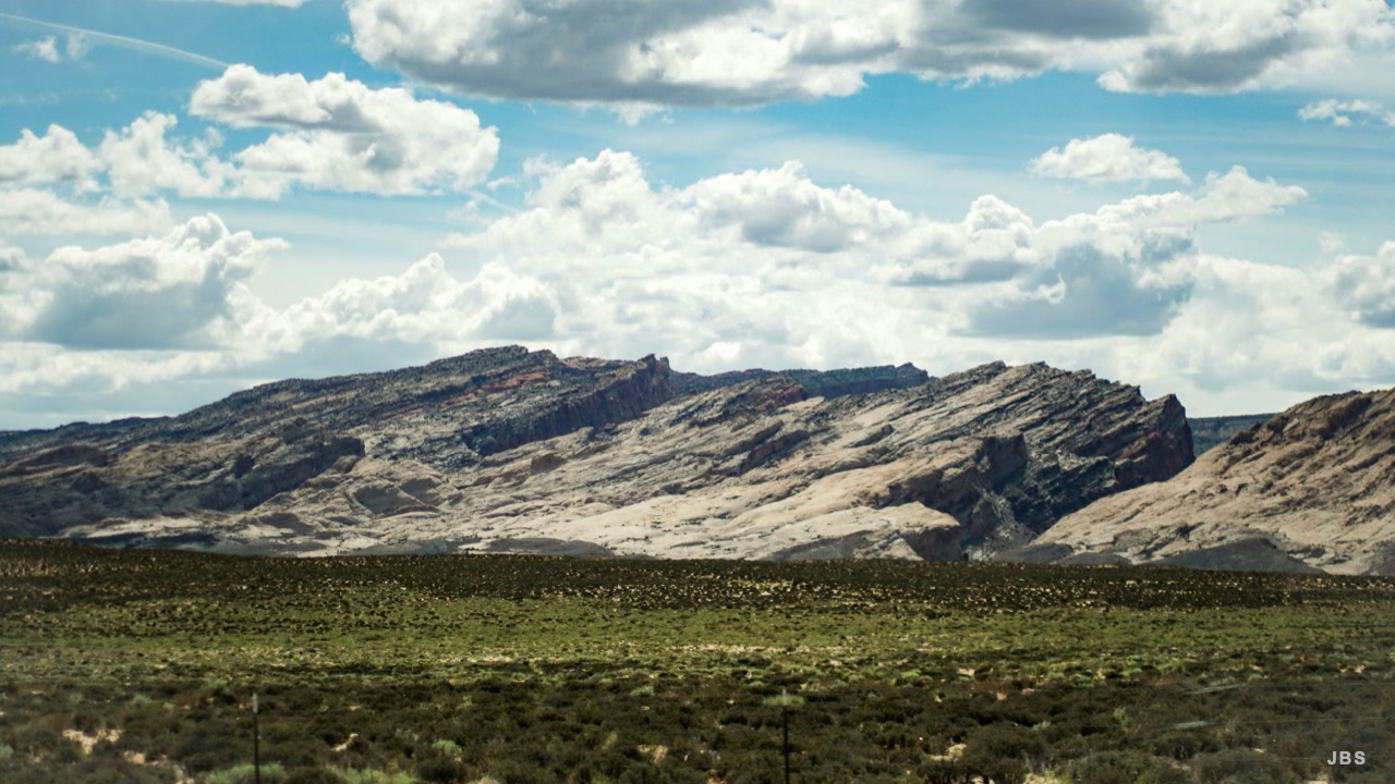 Layered rock formations beneath a sky filled with cumulus clouds