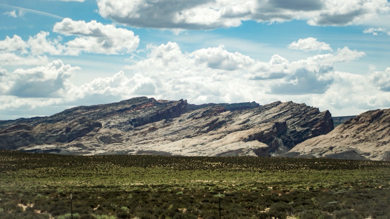 Layered rock formations beneath a sky filled with cumulus clouds