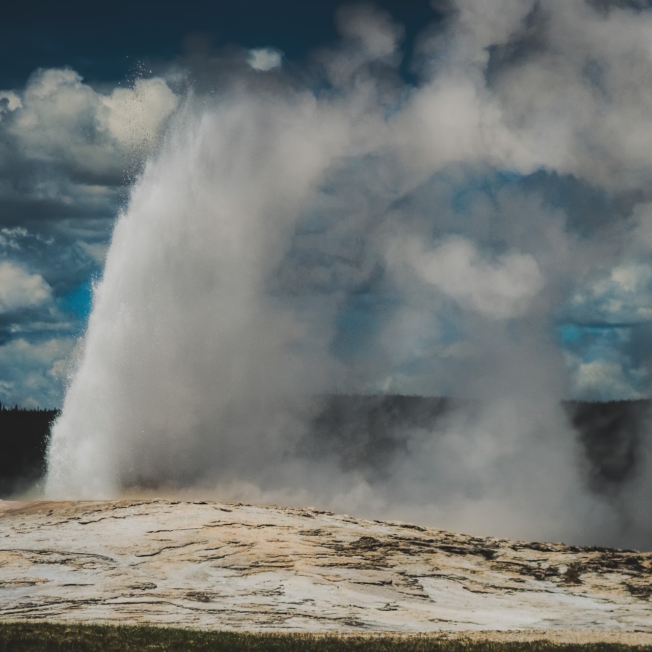 A geyser erupting beneath dark clouds