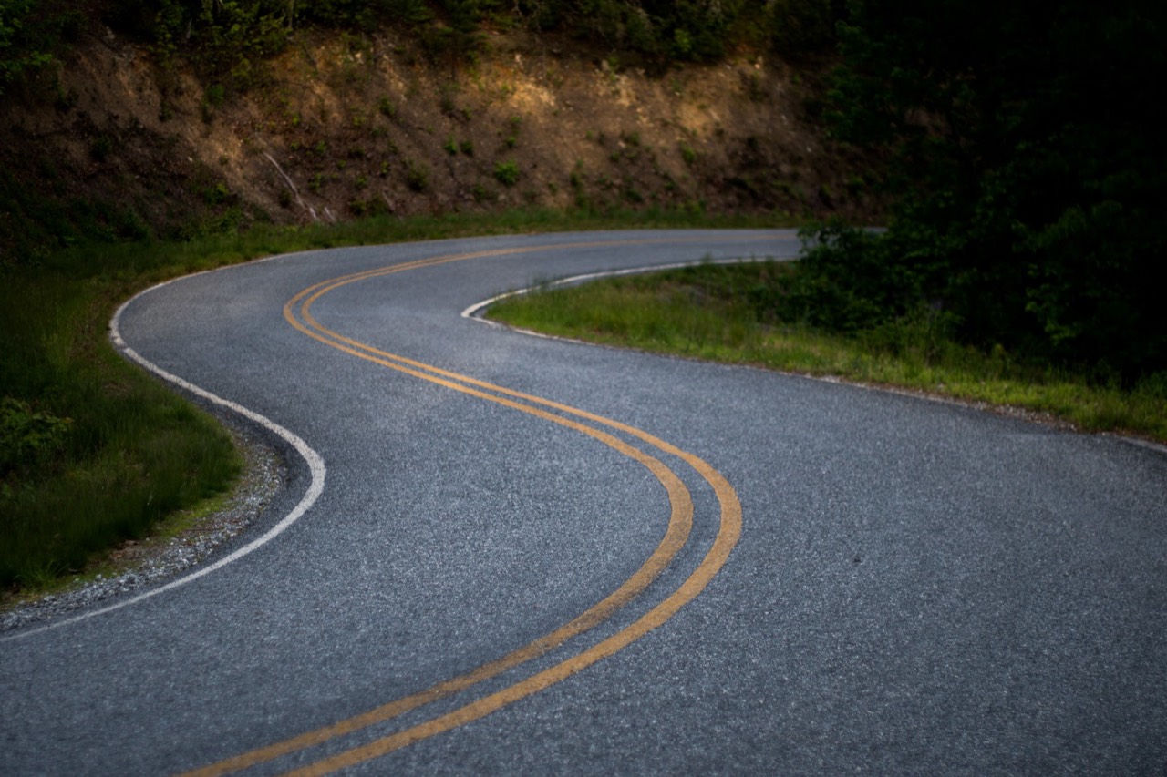A winding two-lane road curving through dense greenery