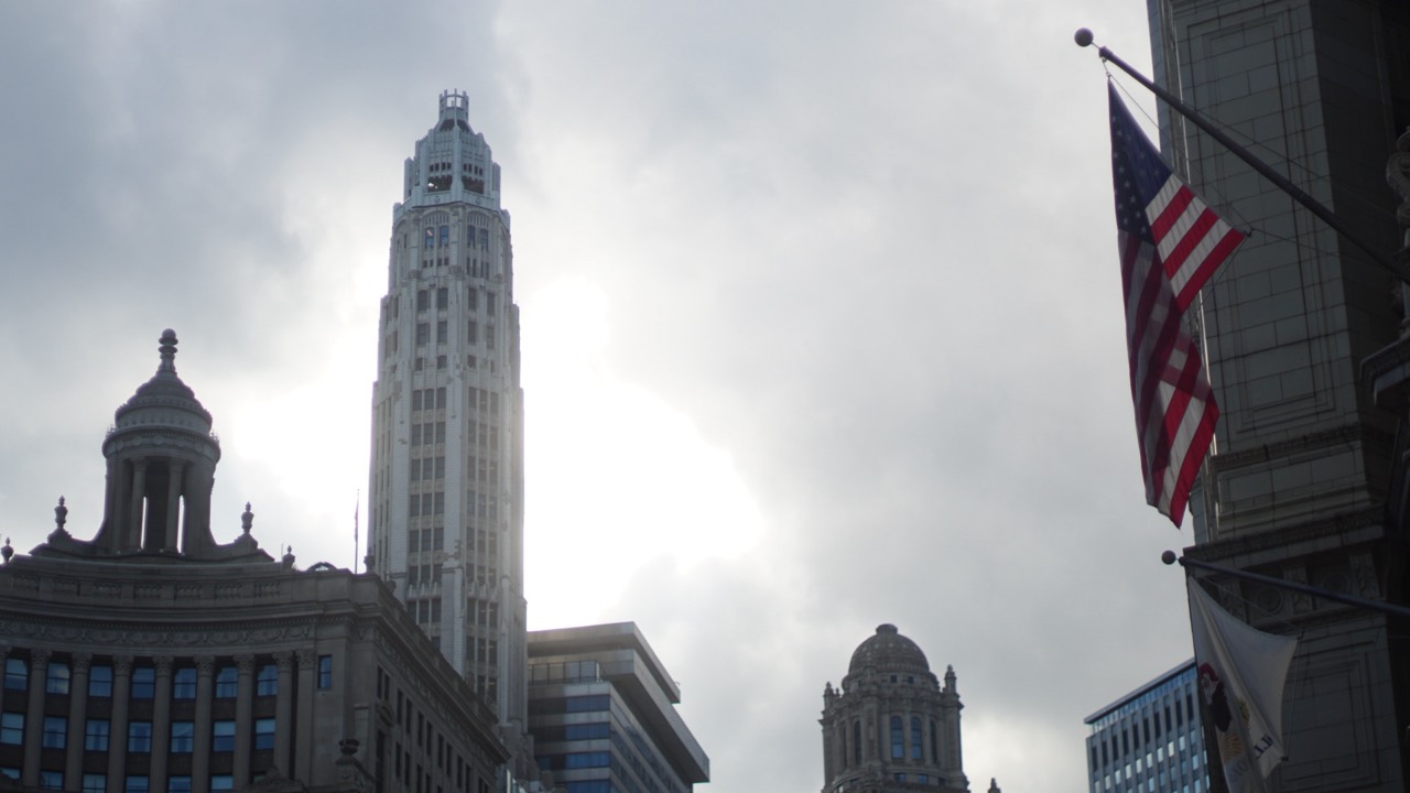 Chicago towers and an American flag beneath an overcast sky