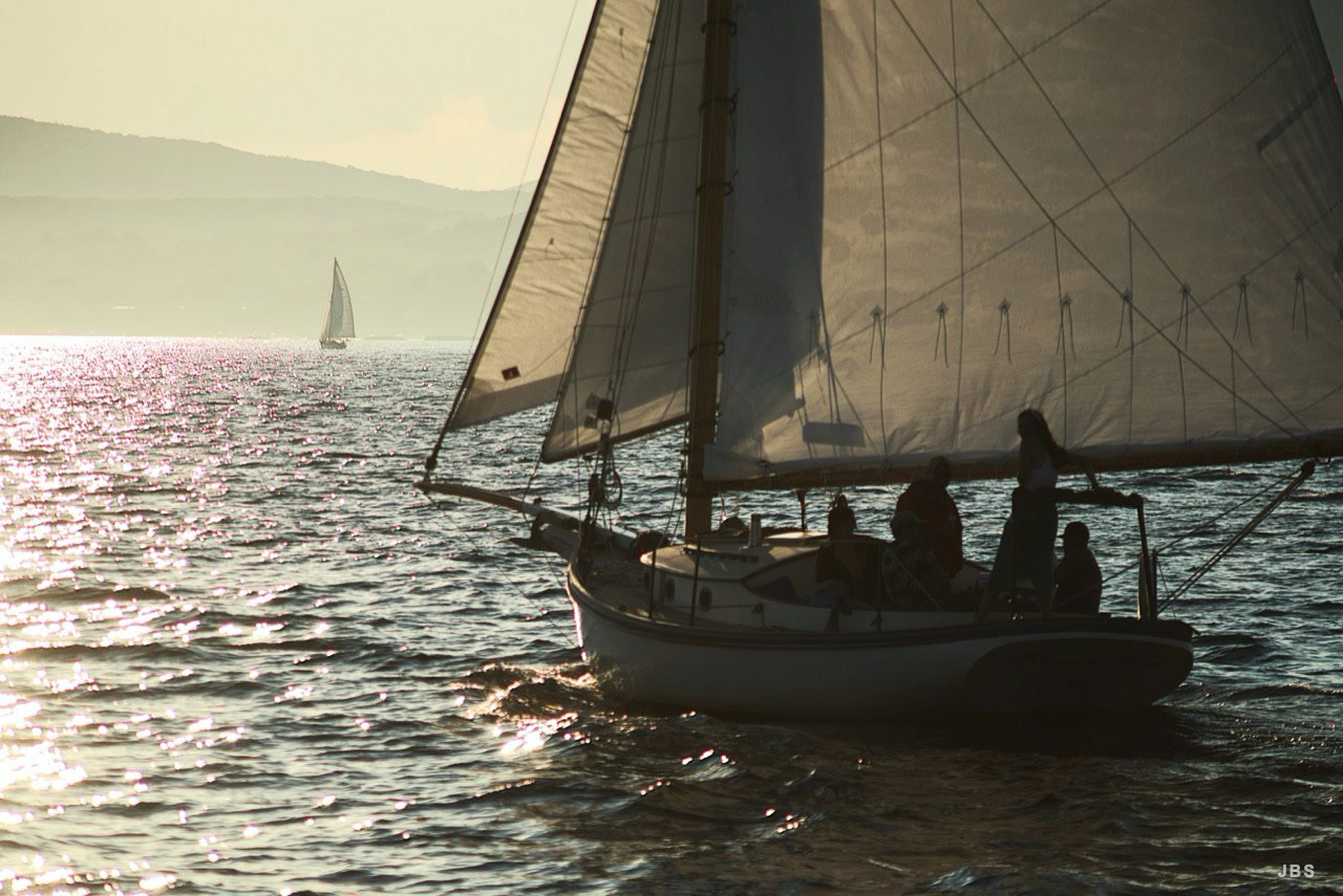 Sailors silhouetted beneath canvas on sunlit water