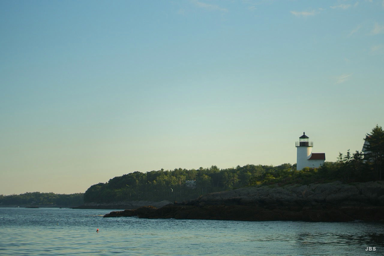 A white lighthouse above a quiet rocky coast