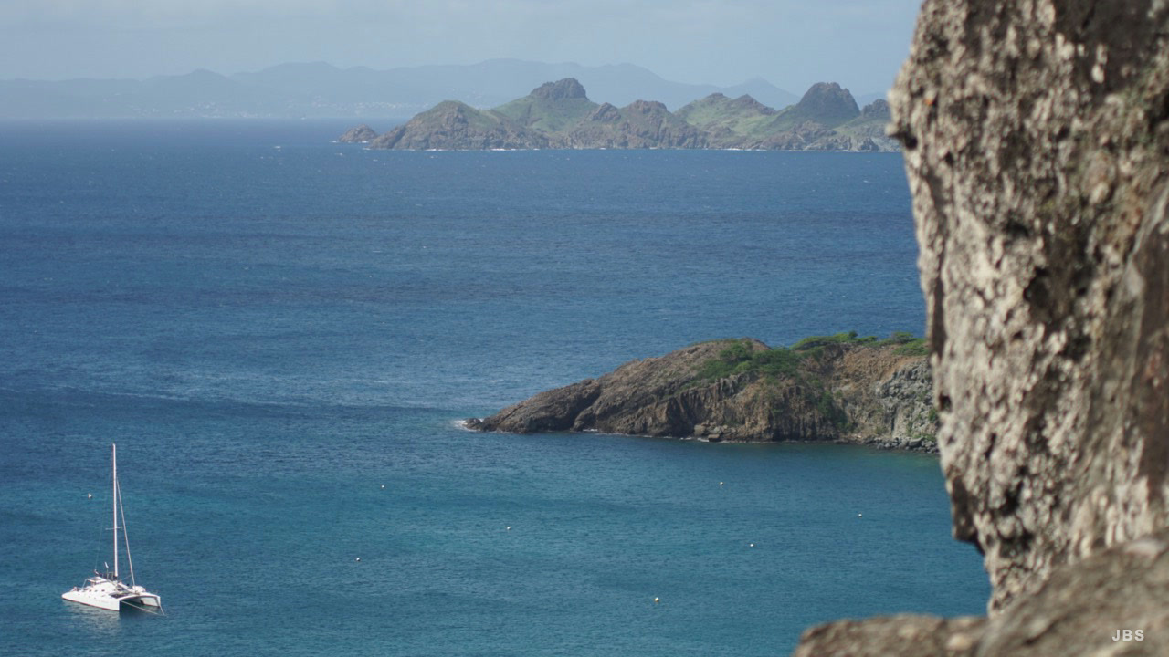 A catamaran in a blue bay with rugged islands on the horizon