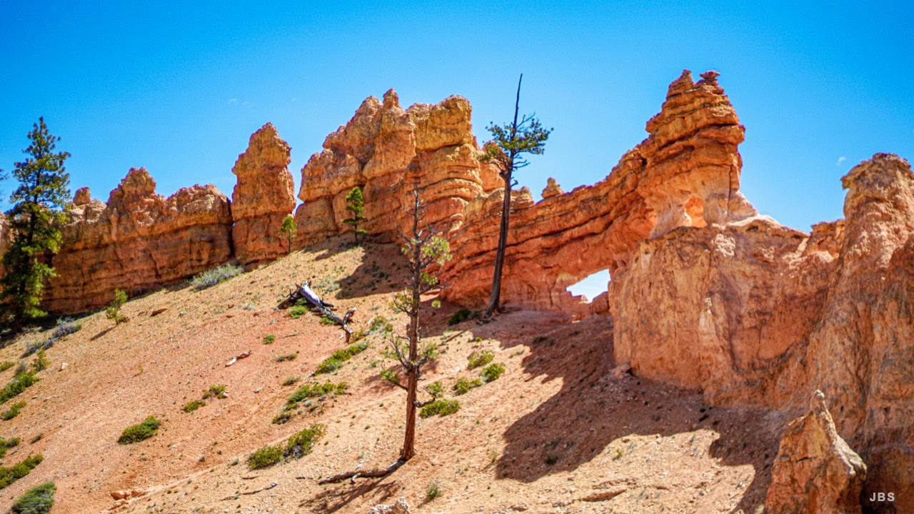Orange hoodoos and a natural arch beneath a vivid blue sky