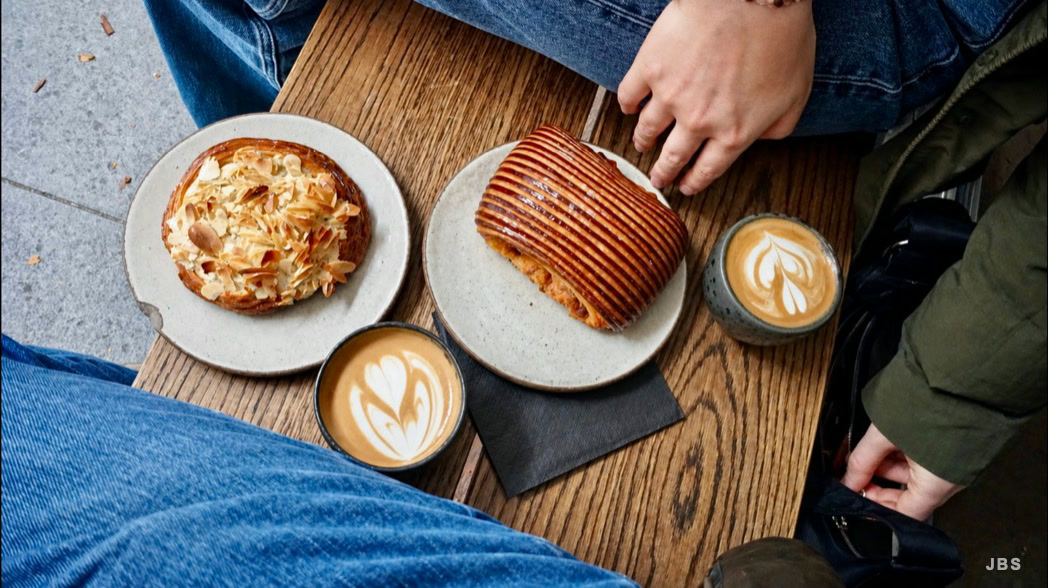 Pastries and two cups of coffee shared around a wooden table